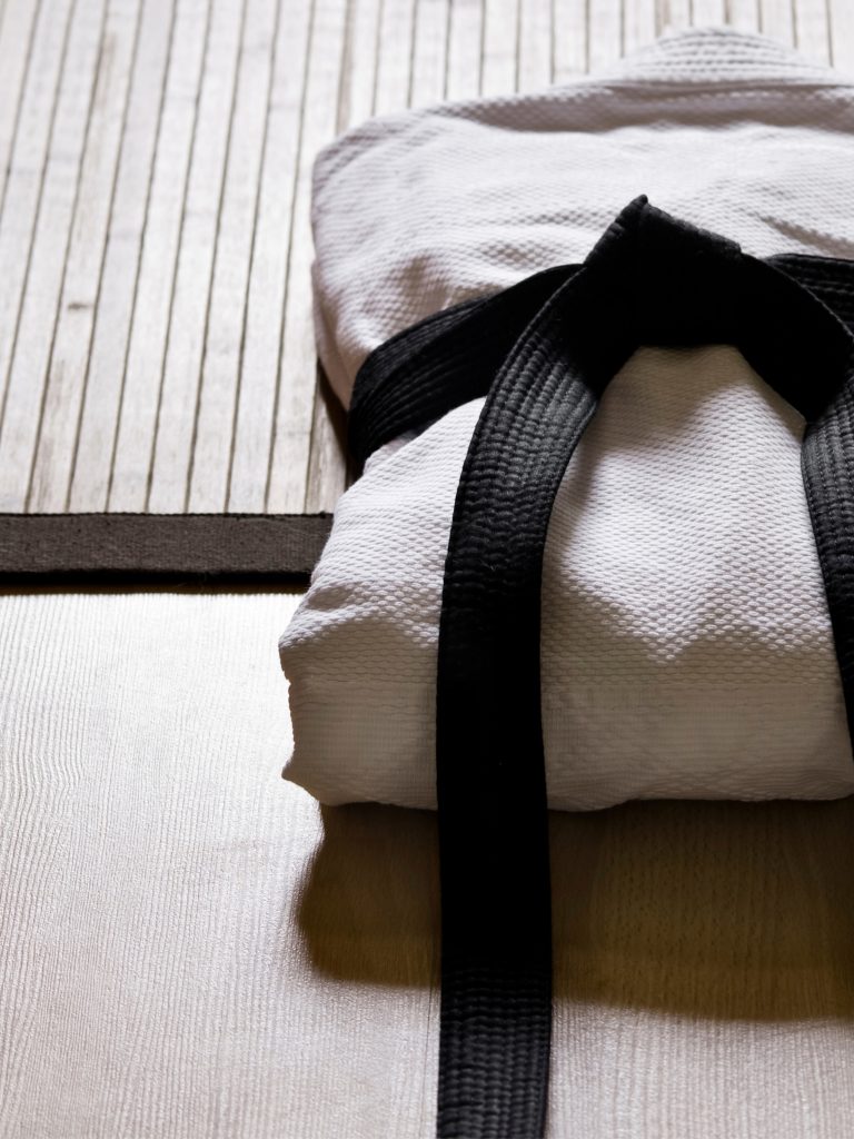 Ein zusammengelegter Judo-Anzug ist mit einem schwarzen Judo-Gürtel zugebunden und liegt auf dem Boden.