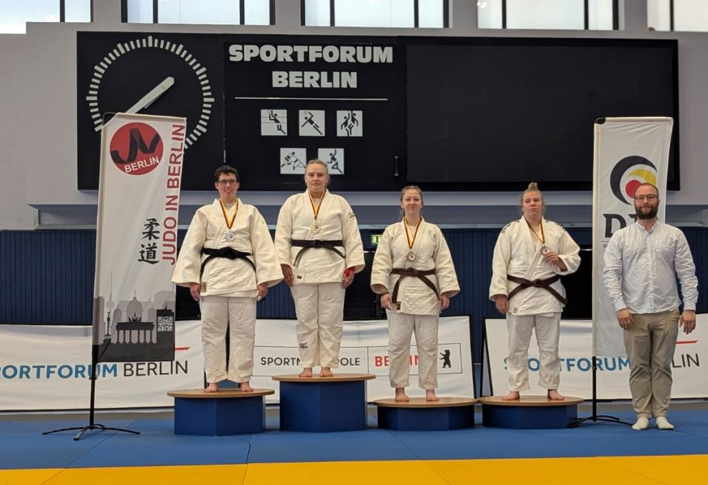 Vier Judo-Frauen, darunter Kim Tepelmann vom PSV Schwerin, stehen im Sportforum Berlin auf einem blauen Siegerpodest.