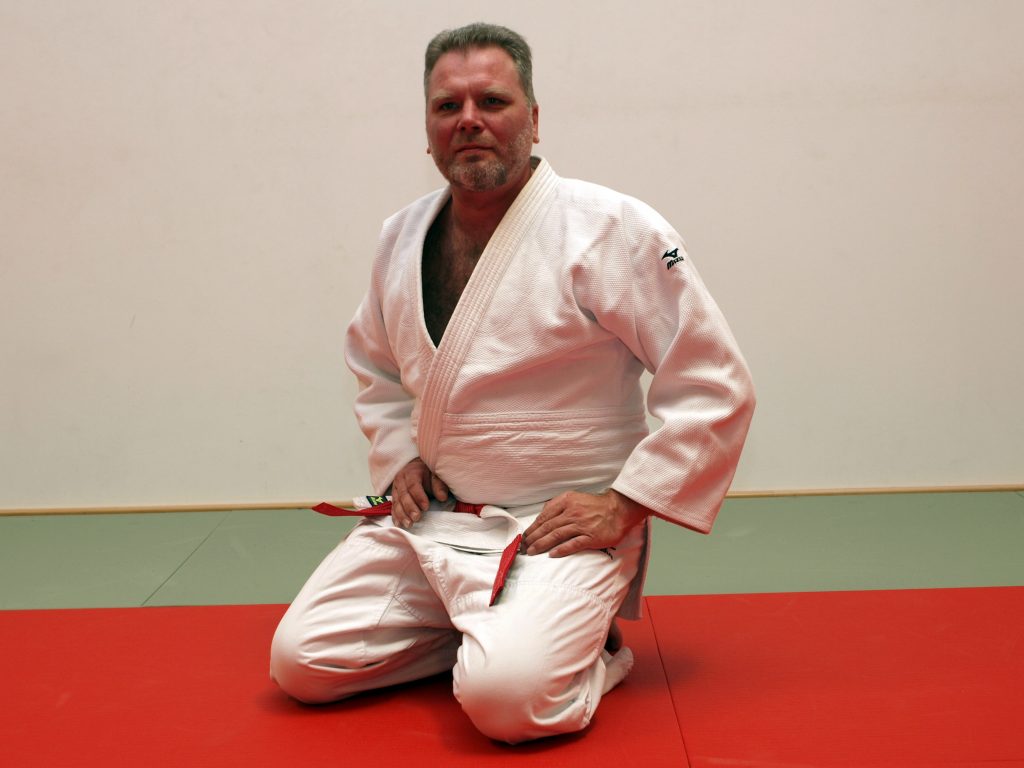 Judo-Trainer Matthias Hermann posiert mit seinem 6. Dan auf der Judo-Matte.