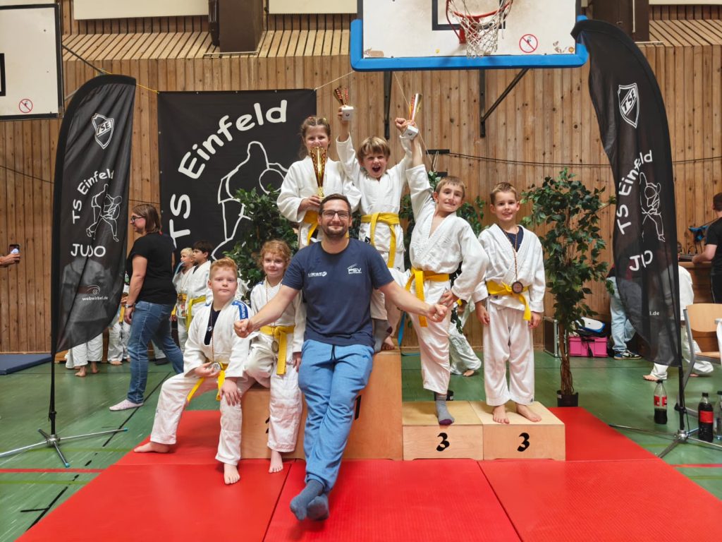 Die jungen Judoka der U9 des PSV Schwerin posieren mit ihrem Trainer mit ihren Medaillen und Pokal auf dem Siegerpodest beim 18. internationalen Schwanen-Cup.